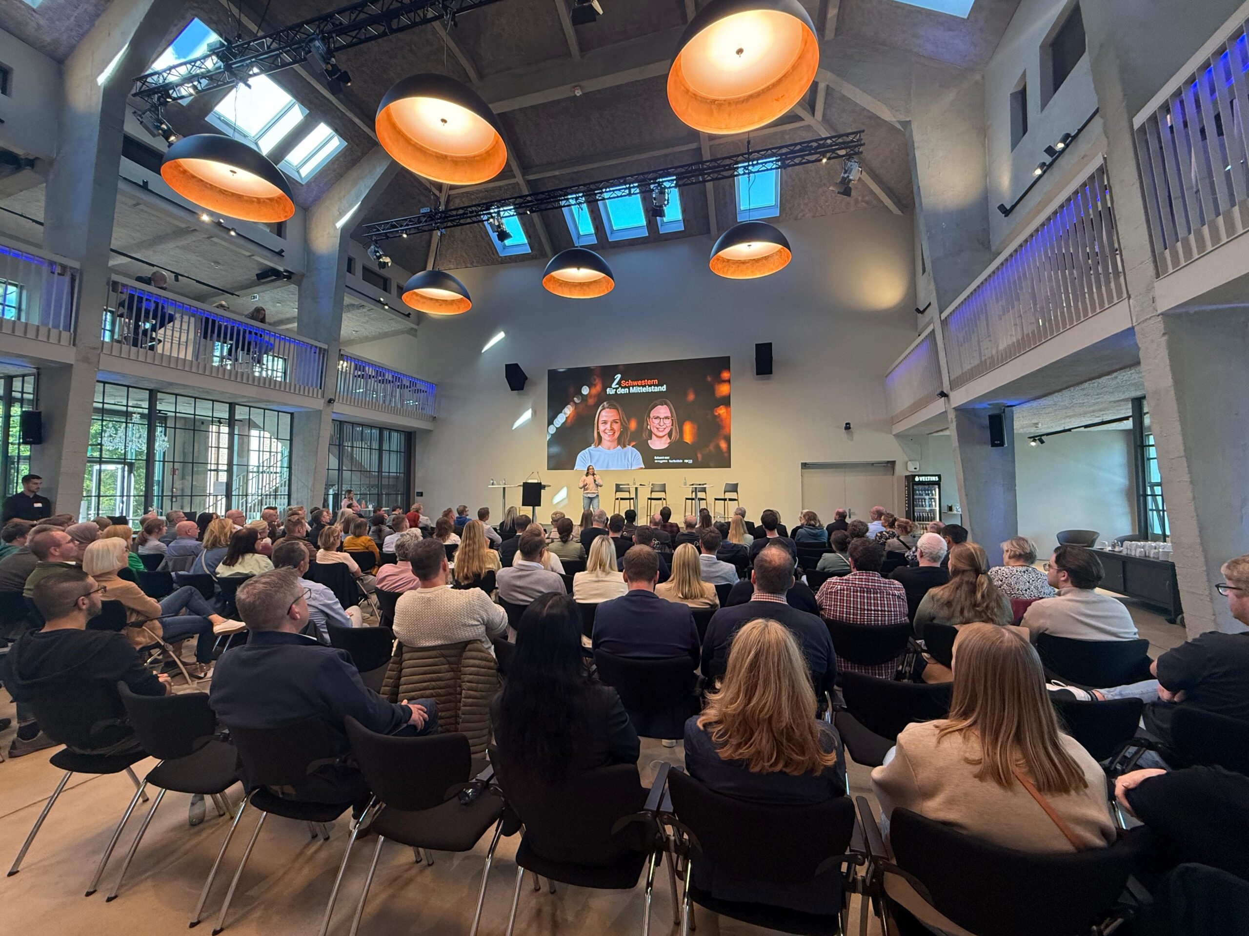 Vortrag von Rinker & Rinker bei einer Fachkräfte-Veranstaltung vor Publikum mit Präsentationsscreen.